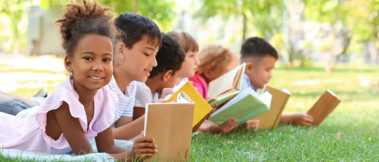 Six homeschool students outside on grass with books in hand