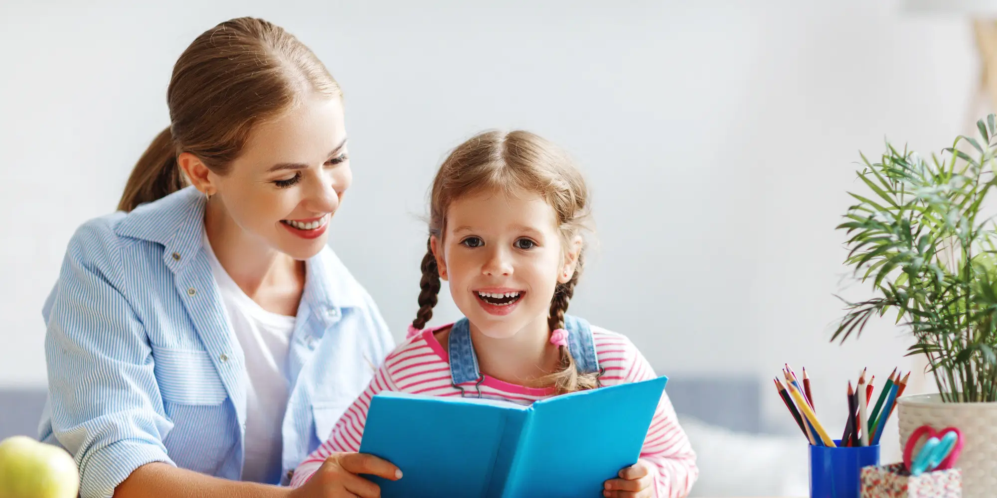 Mother and child daughter doing homeschool writing and reading at home